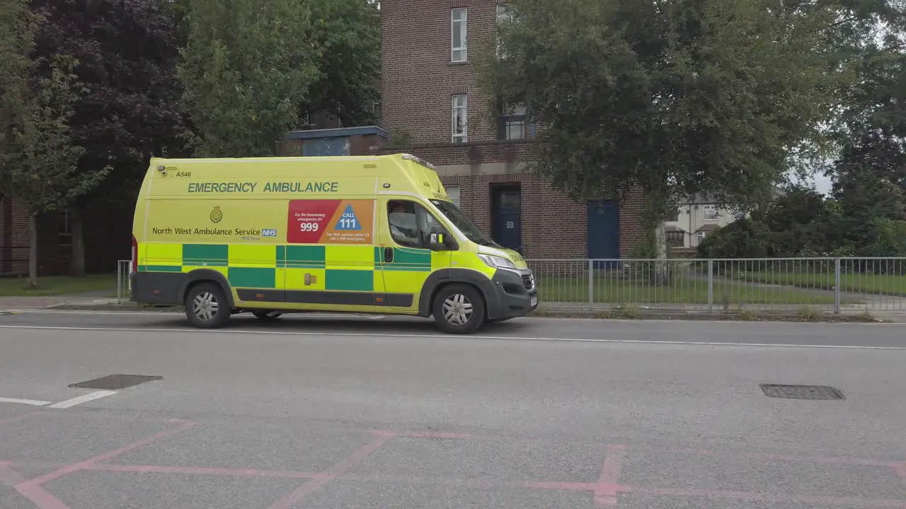 Merseyside yellow ambulance leaving Warrington hospital slow motion