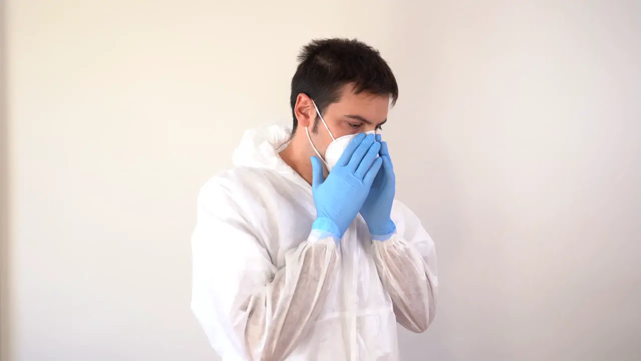 Doctor in PPE suit putting on a face mask in profile to the camera