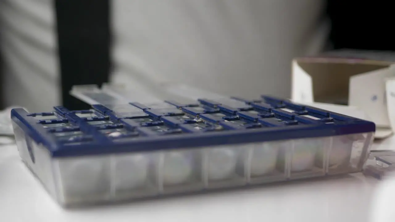 Old man sorting medicine pills by weekly organizer box Extreme close up