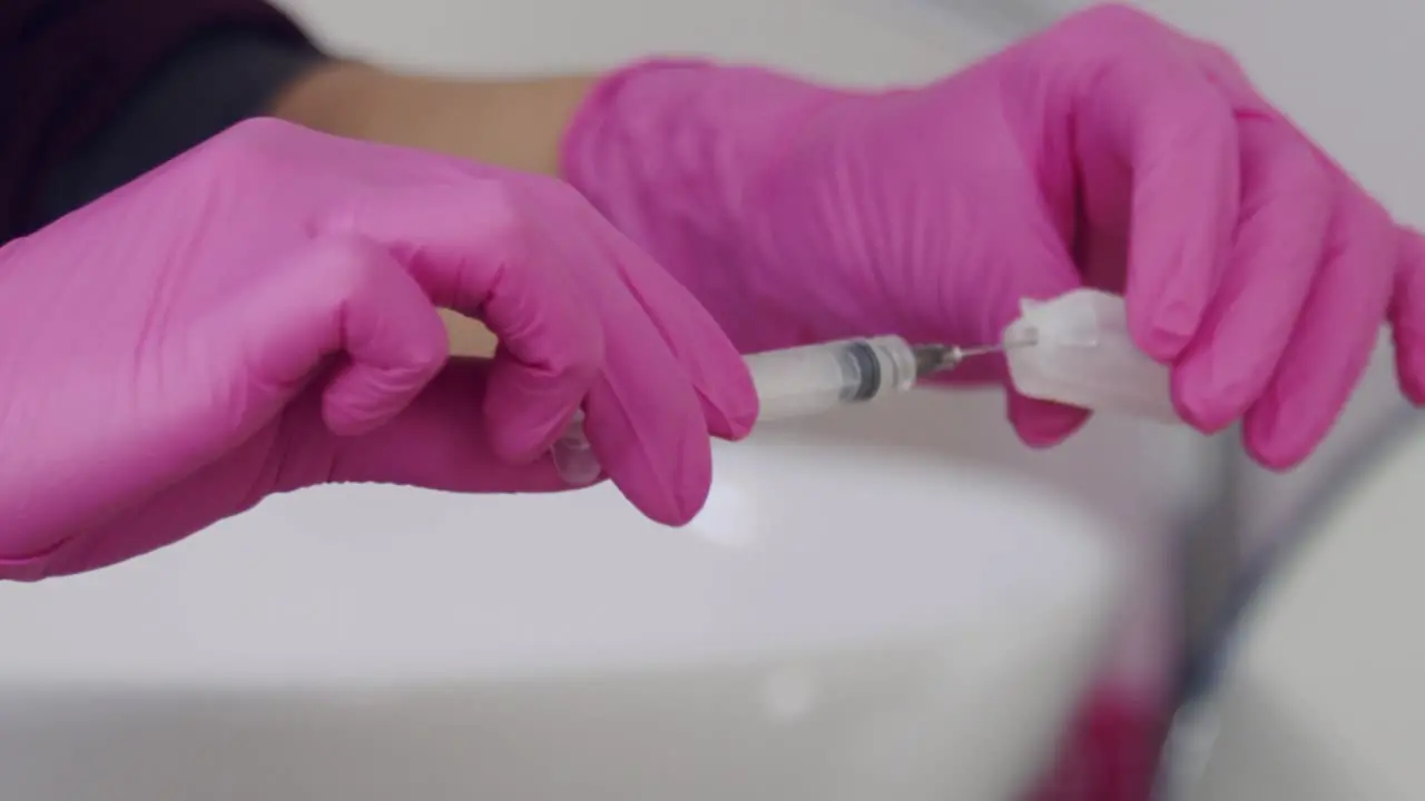 Woman's hands seen drawing liquid from a vial into a syringe isolated close up