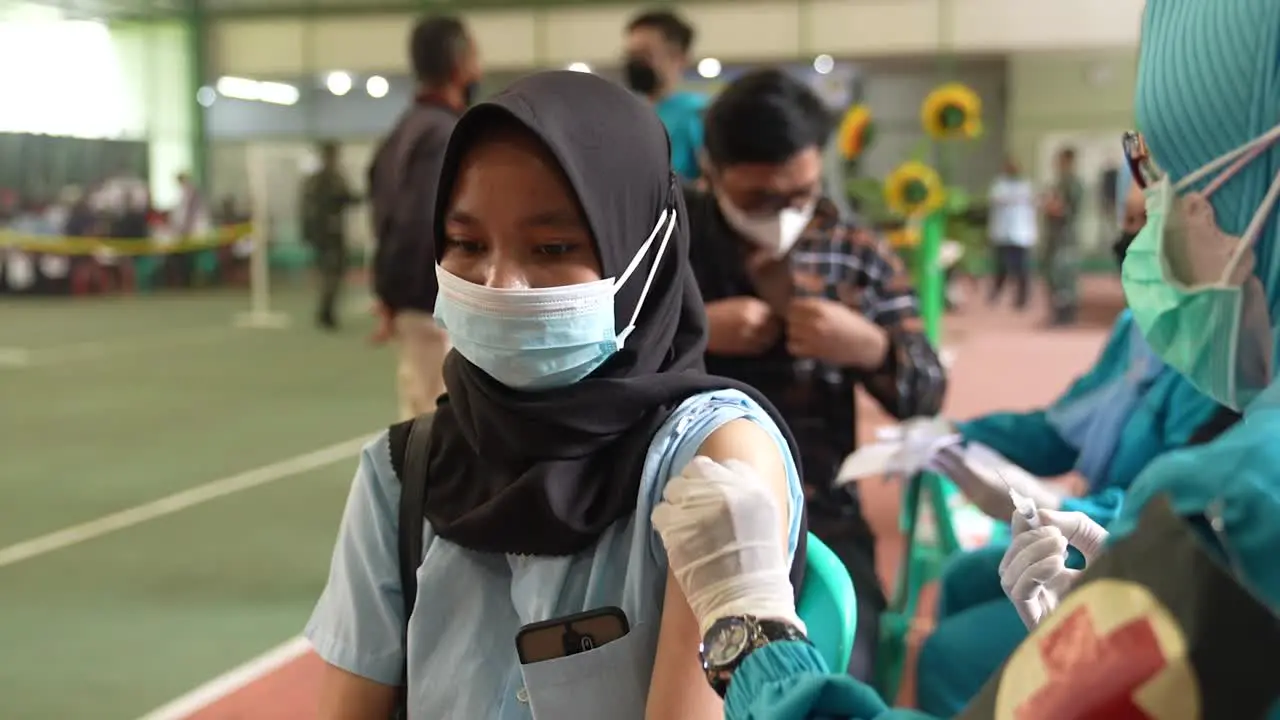 Medical Nurse in Safety Gloves and Protective Mask Making Vaccine Injections for Female Patient at vaccination rush