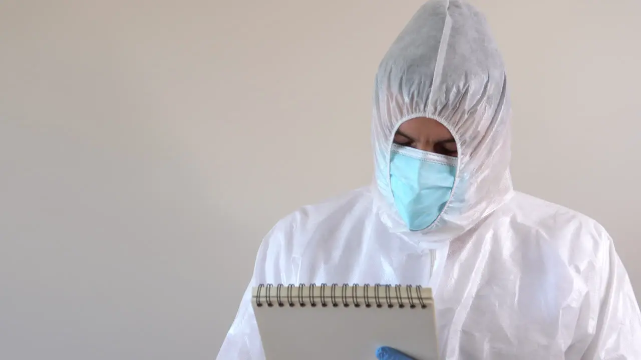 Doctor in PPE suit writing in a notebook