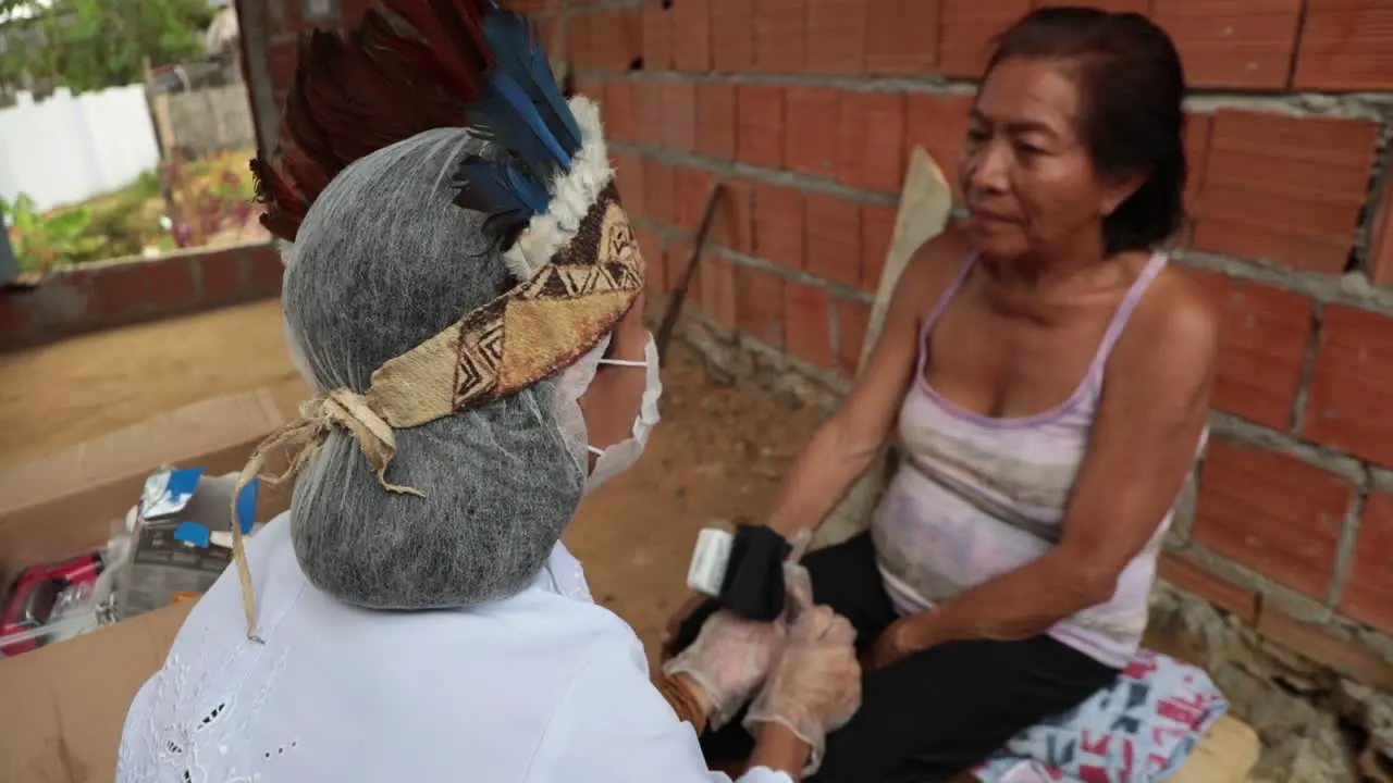 Amazonian tribal healer volunteering as a COVID-19 nurse speaking with a patient in her tribe