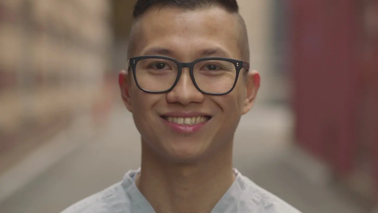 A nurse in black framed glasses looks up and smiles