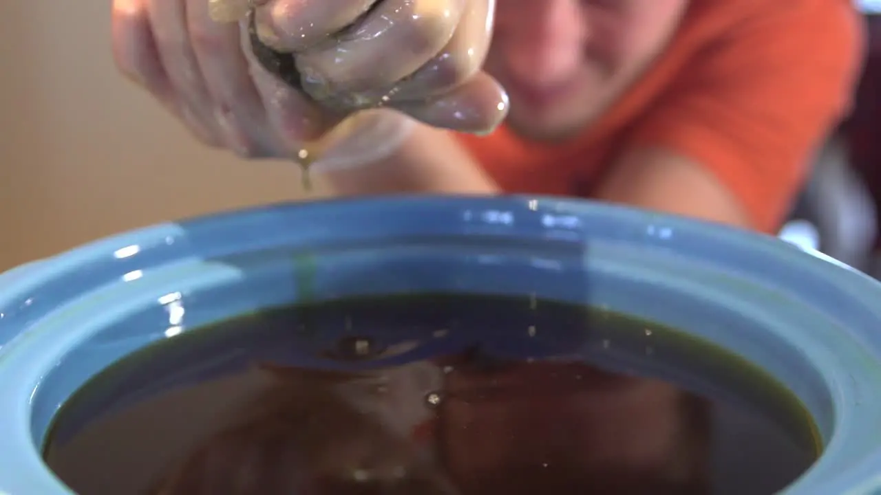 Caucasian Person Squeezing Contents Of Tea Bag Unto Pot close up shot