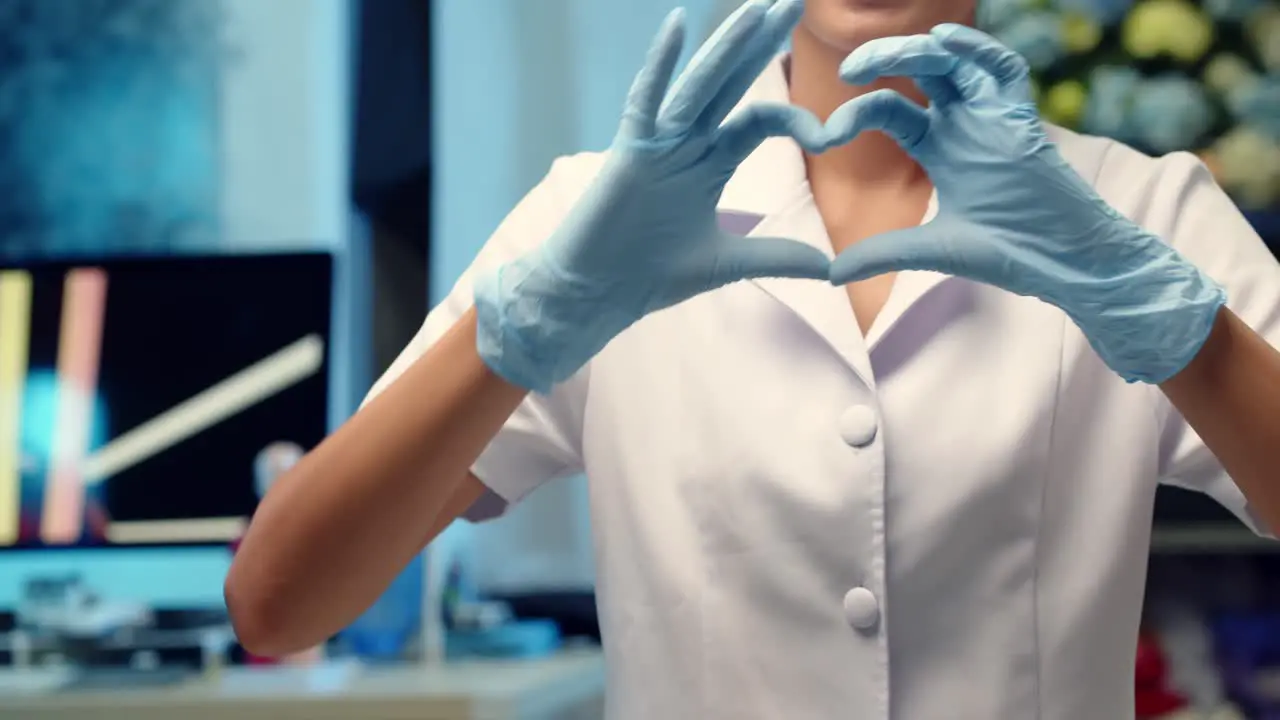 A nurse makes a heart shaped hand sign to a patient as a kind gesture