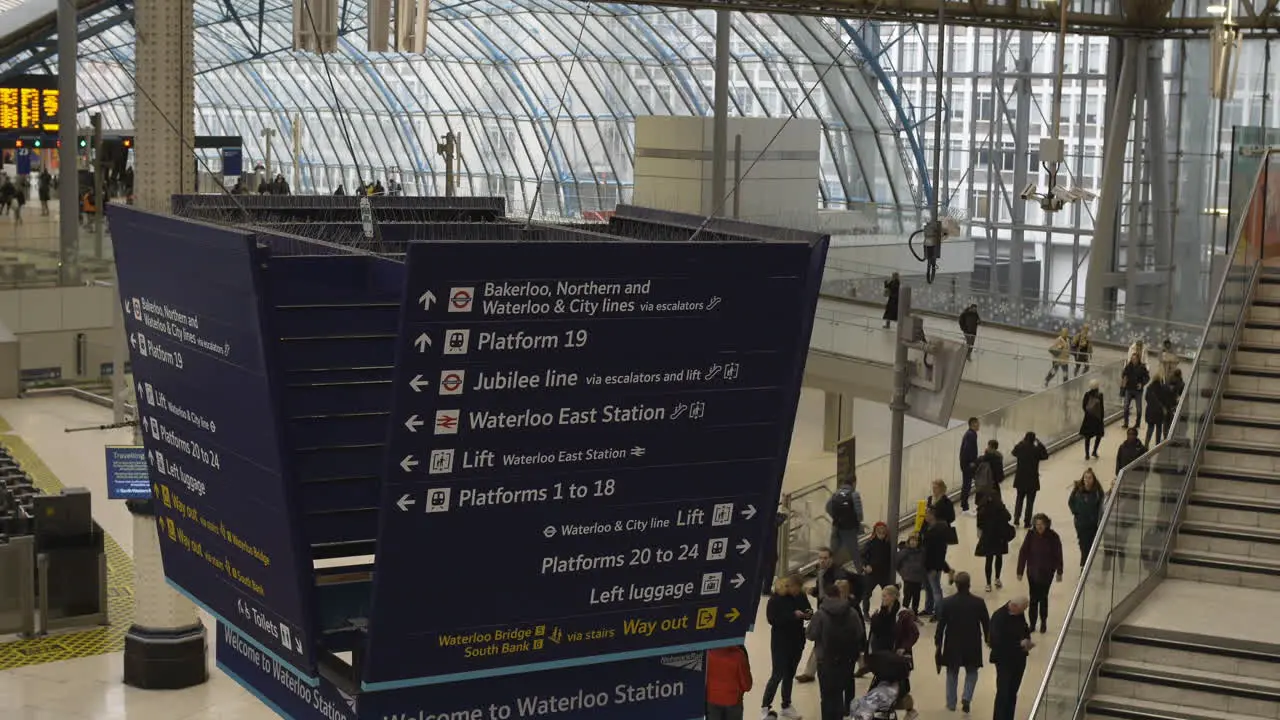 Directional sign in Waterloo train station with commuters walking London UK