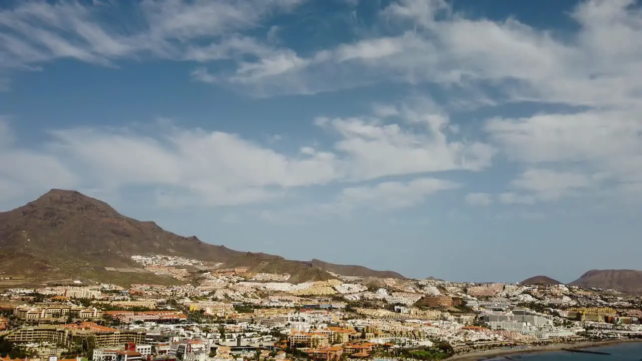 Beautiful Seaside with Mountains In The Background And Buildings At the Side Blue Sea Drone Shot