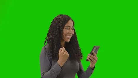 Woman Looking At Mobile Phone And Celebrating Good News Against Green Screen 2