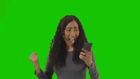 Woman Looking At Mobile Phone And Celebrating Good News Against Green Screen 1