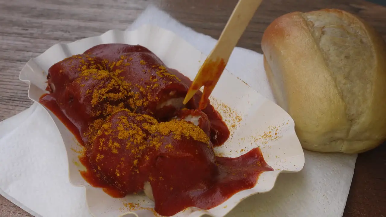 Eating real German currywurst sausage with a wood pick