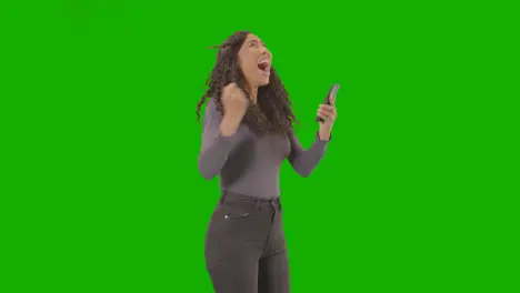 Woman Looking At Mobile Phone And Celebrating Good News Against Green Screen 6