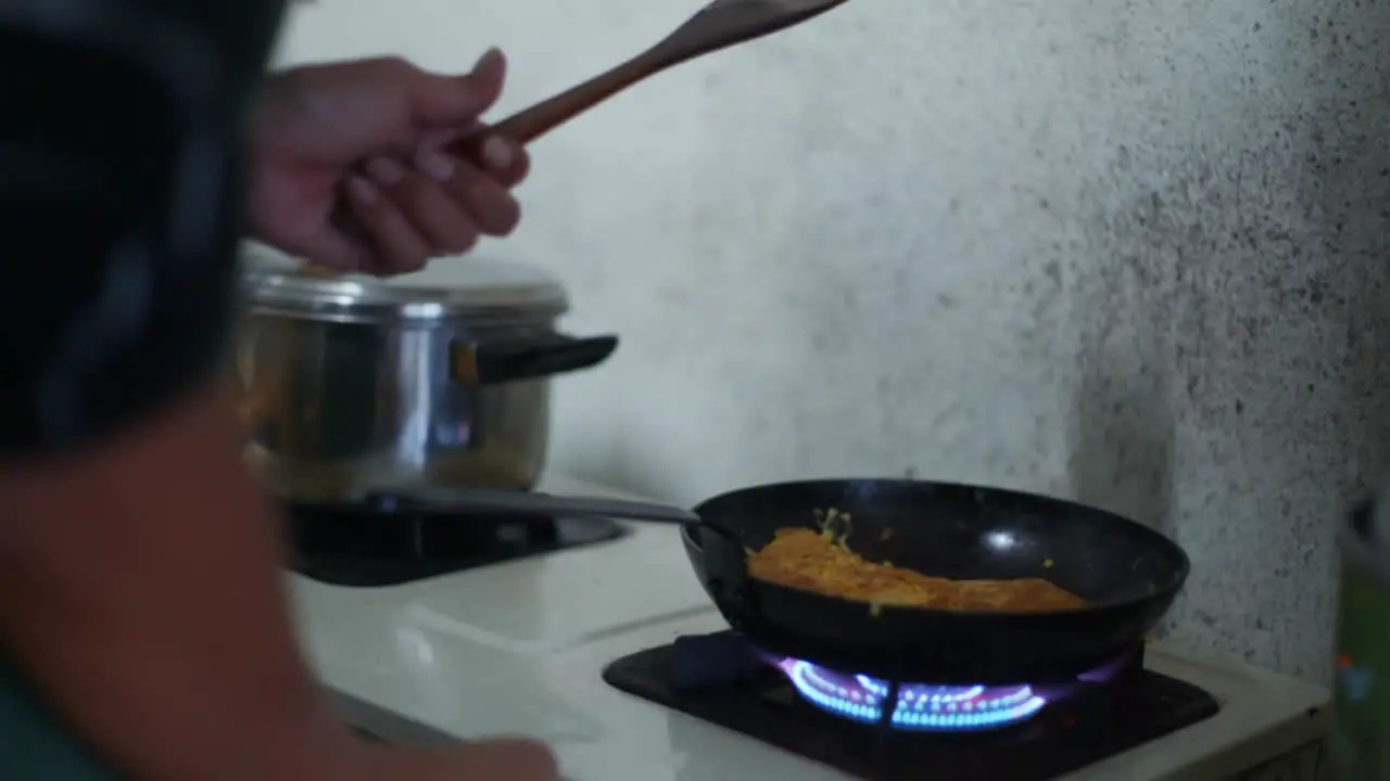 Hot fry pan with fried egg placed on blue gas flame stove filmed as medium close up shot in slow motion