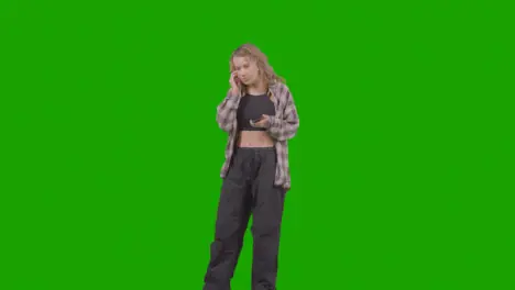 Full Length Studio Shot Of Young Woman Listening To Music On Mobile Phone And Dancing Against Green Screen 1