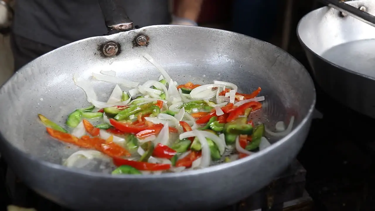 Professional chef fries vegetables to prepare white sauce Pasta at a street food shop at Chat Gali in Agra India on 07 March 2021