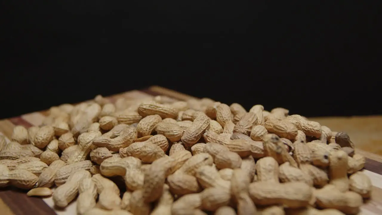 Spinning wide angle of a pile of peanuts on a cutting board with a black background