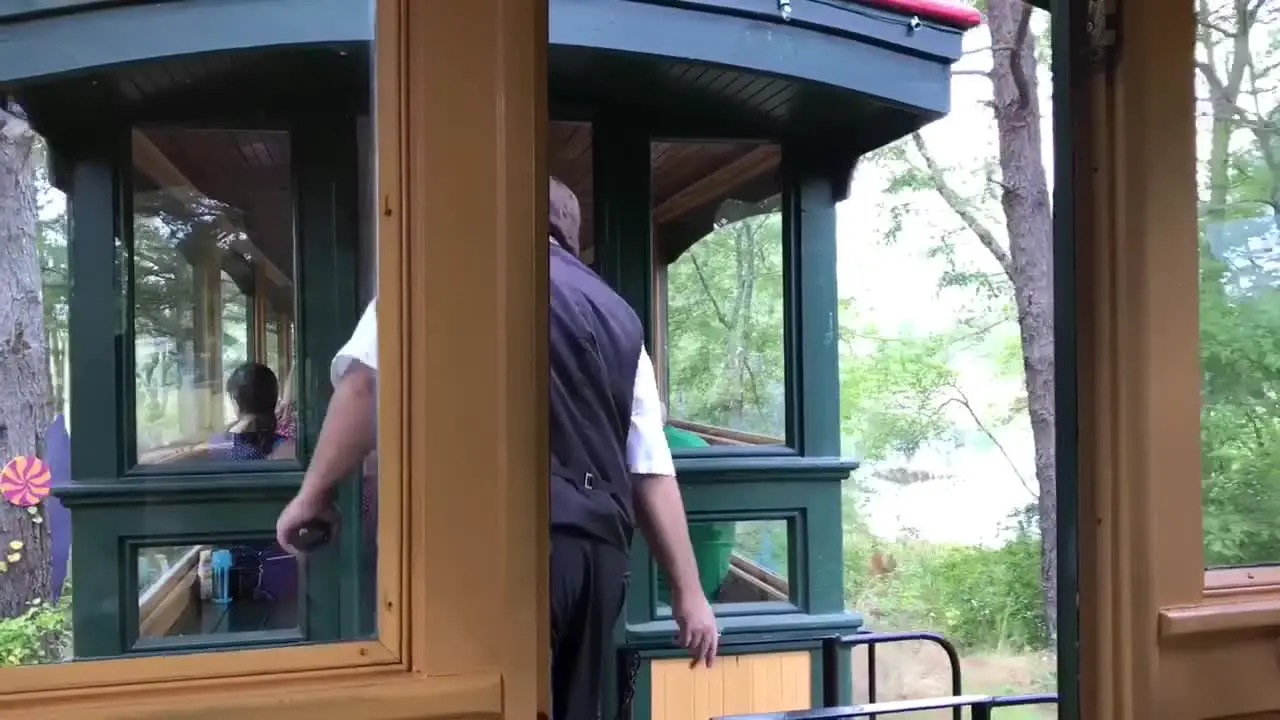 A train conductor checking tickets and crossing over to the next train at Thomas Land and Edaville Family Theme Park in Massachusetts