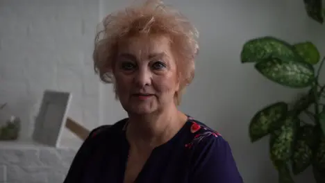 beautiful elderly woman lady portrait looking in camera with intense face sitting in the living room of her house healthy elderly woman