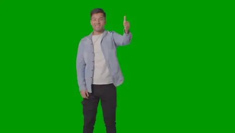 Studio Shot Of Casually Dressed Young Man Giving Thumbs Up Gesture Against Green Screen 3