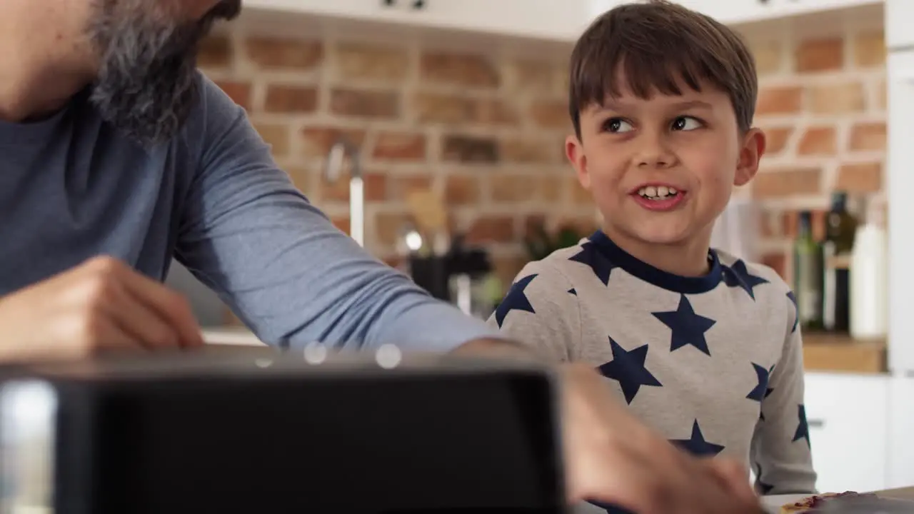 Close up video of father and son eating breakfast in the kitchen