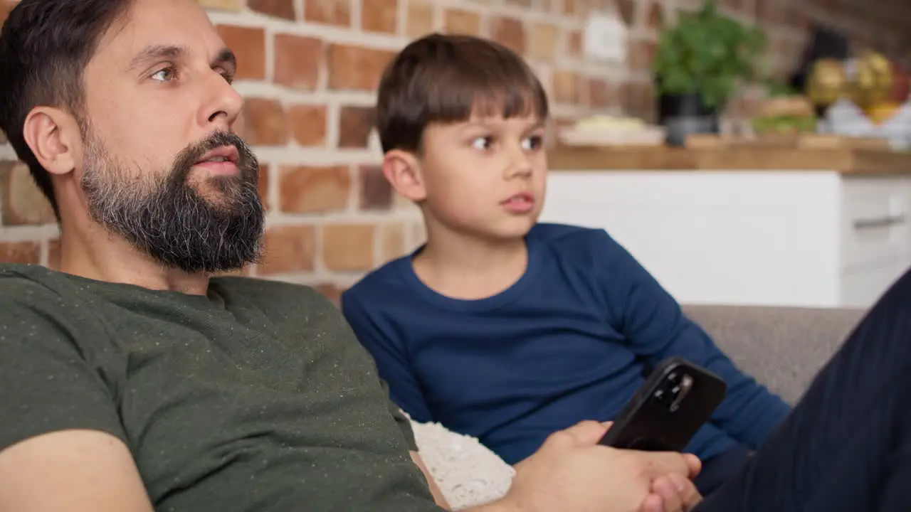 Close up video of father and son watches TV at home