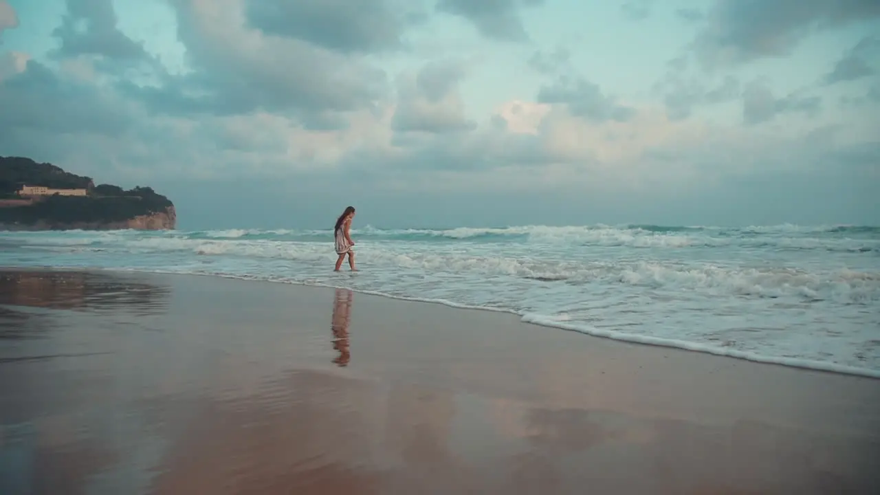 Happy girl enjoying morning at seaside Young woman looking on waves at sea surf