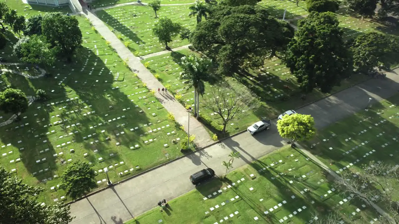 Drone shot of people walking in the cemetery towards the road