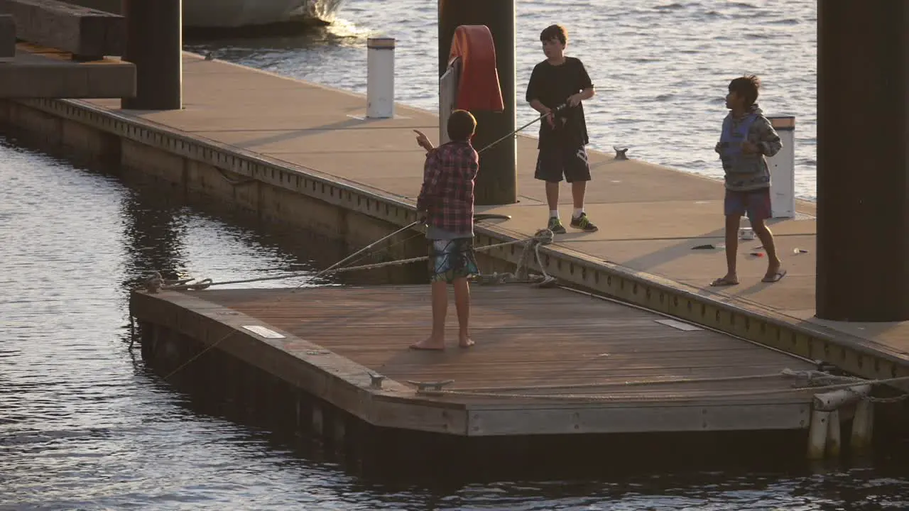 Three kids fishing on pontoon on the harbour Newcastle