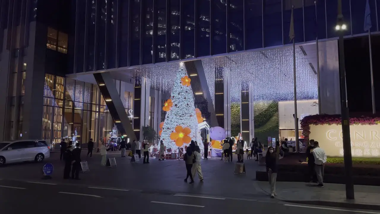 Chinese people walking by the hotel entrance with Huge Christmas tree installation at night