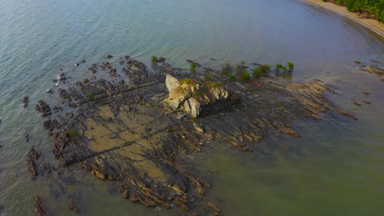 Drone shot turning around of a rock front of a tropical beach during the day