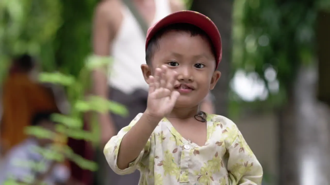 happy burmese child with cleft lip waving into the camera