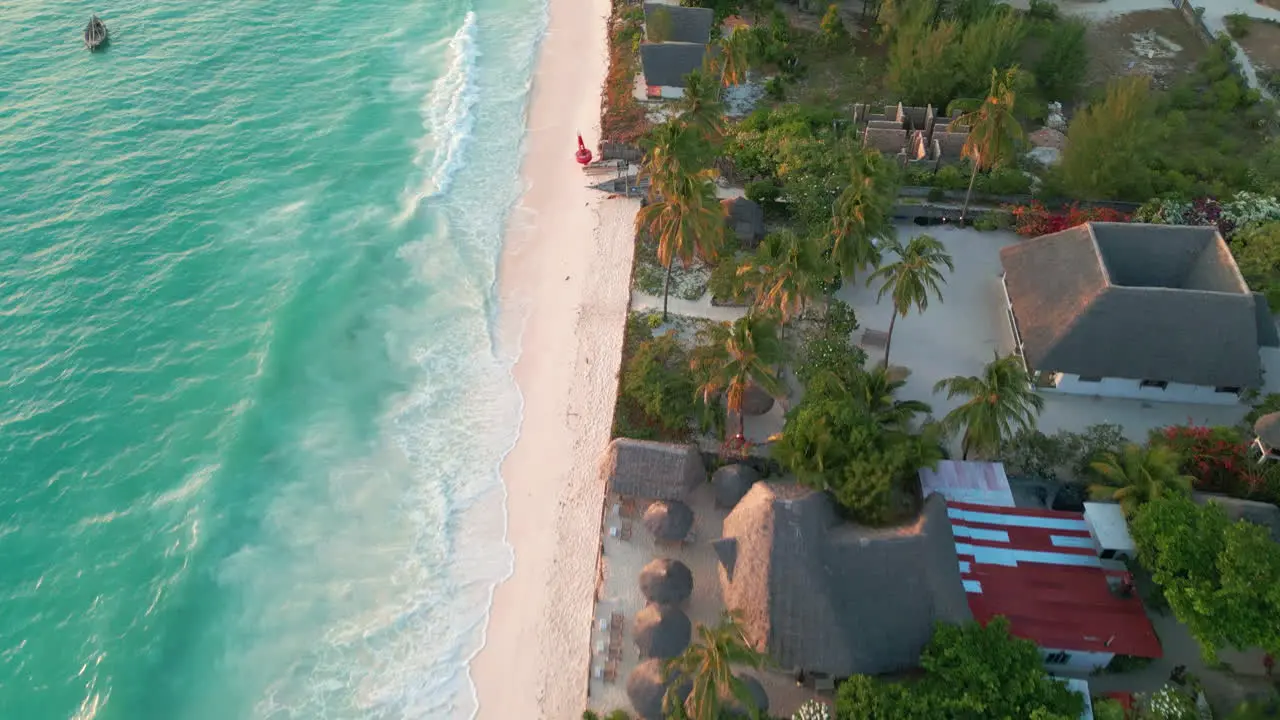 Aerial view of a tranquil empty beach with hatch-roofed villas