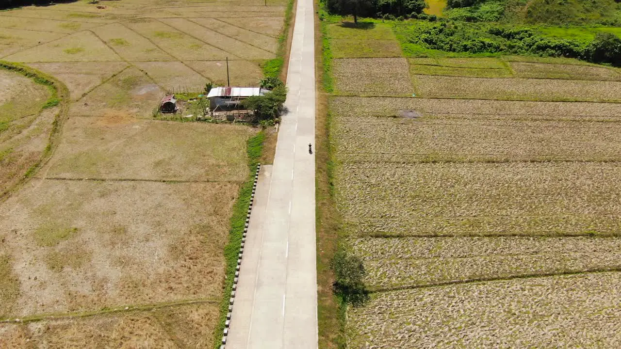 Motorbike driving at an empty street with farmland around