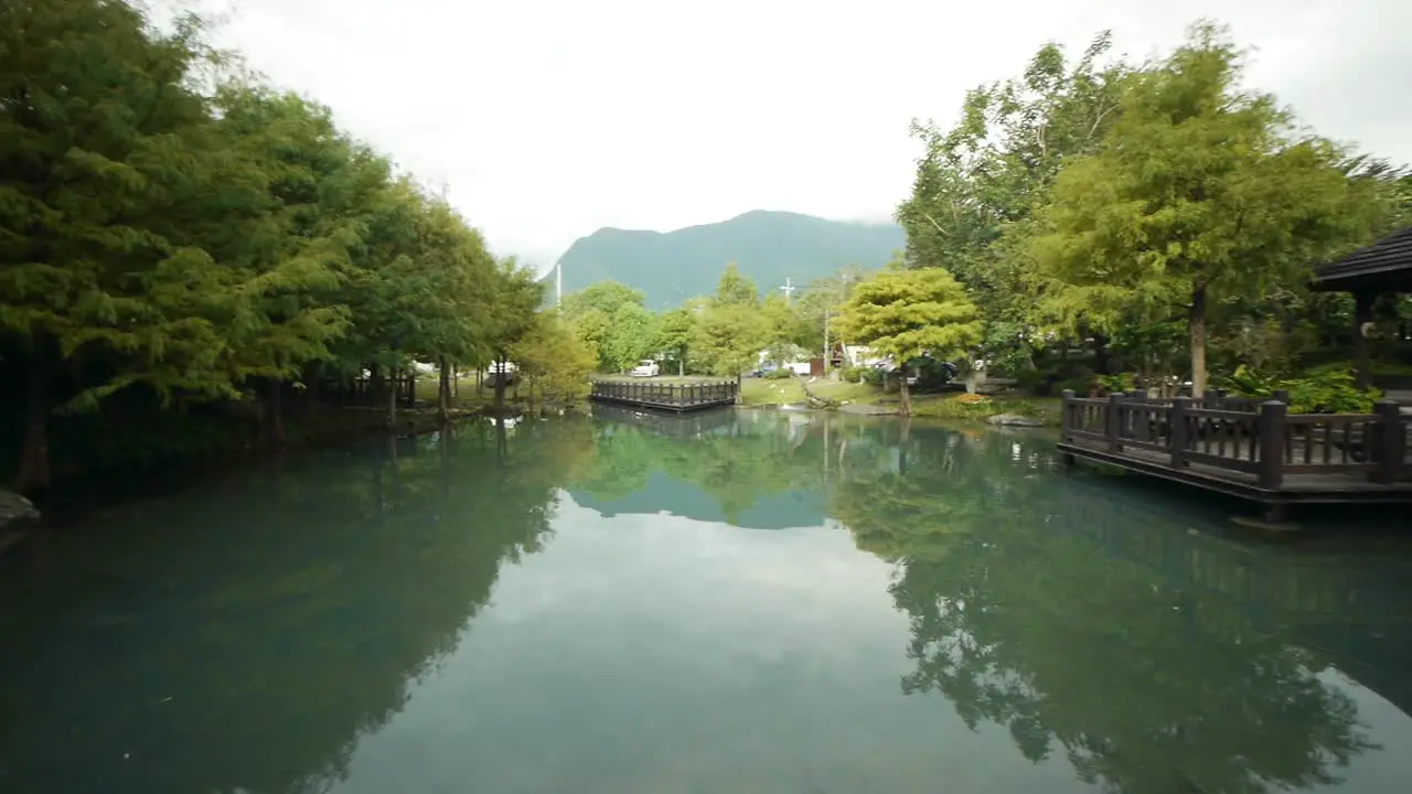 Mountain and trees reflecting on pond with pagoda viewing area