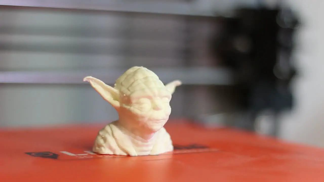 A 3D printed model of Yoda sits on a 3D Printer