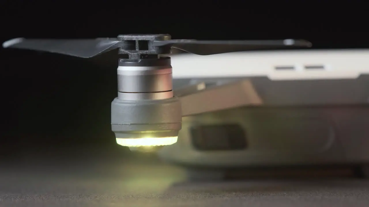 Track across the right hand side and propellers of a white DJI Spark drone with drone lights flashing