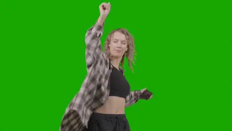 Studio Shot Of Young Woman Listening To Music On Mobile Phone And Dancing Against Green Screen 3