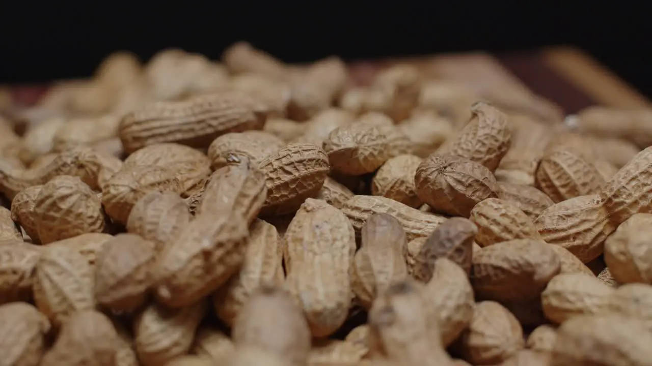 Spinning pile of peanuts on cutting board close up with black background