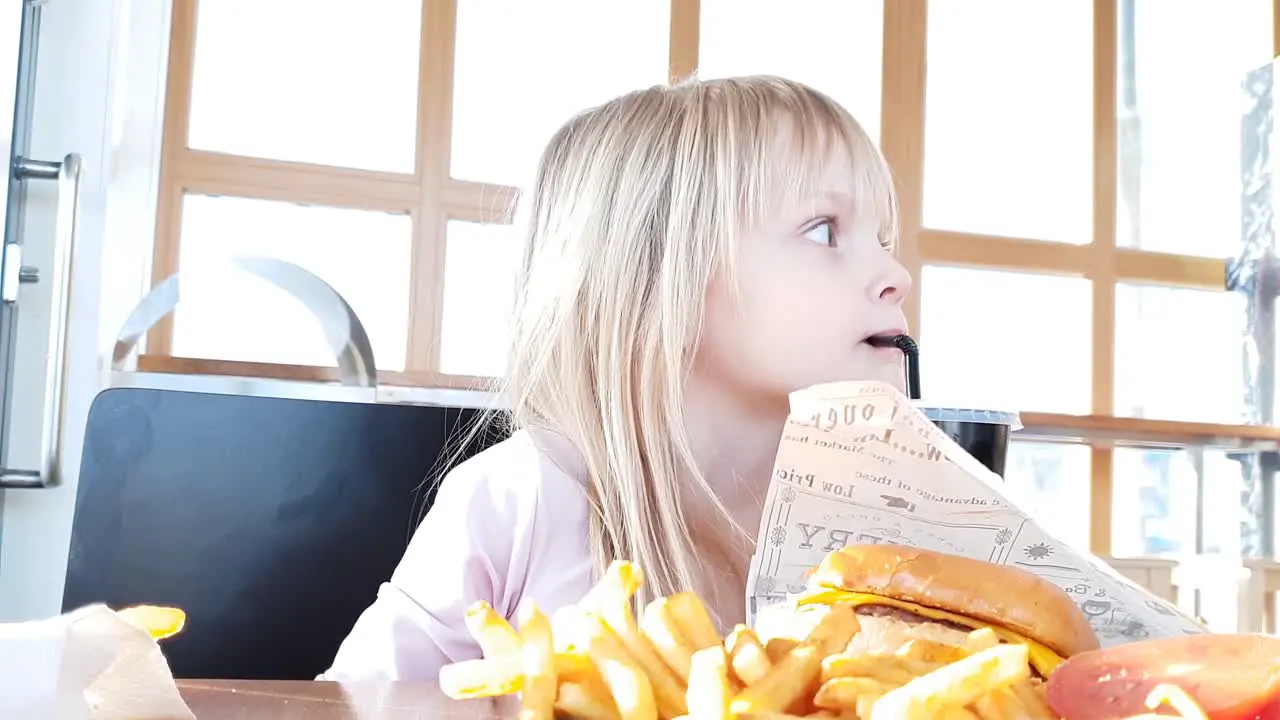 blonde girl at fast food restaurant sipping on soft drink soda lemonade slowmo