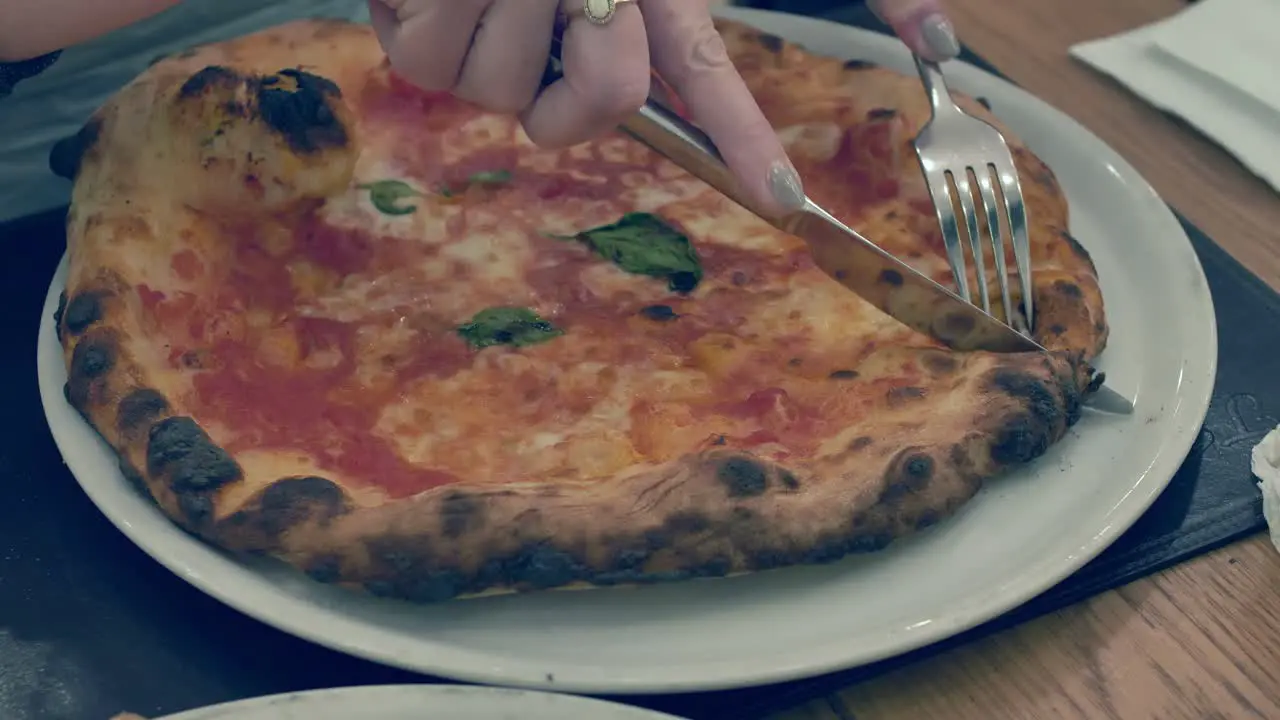 Lady Cutting hot steaming Pizza and sharing half