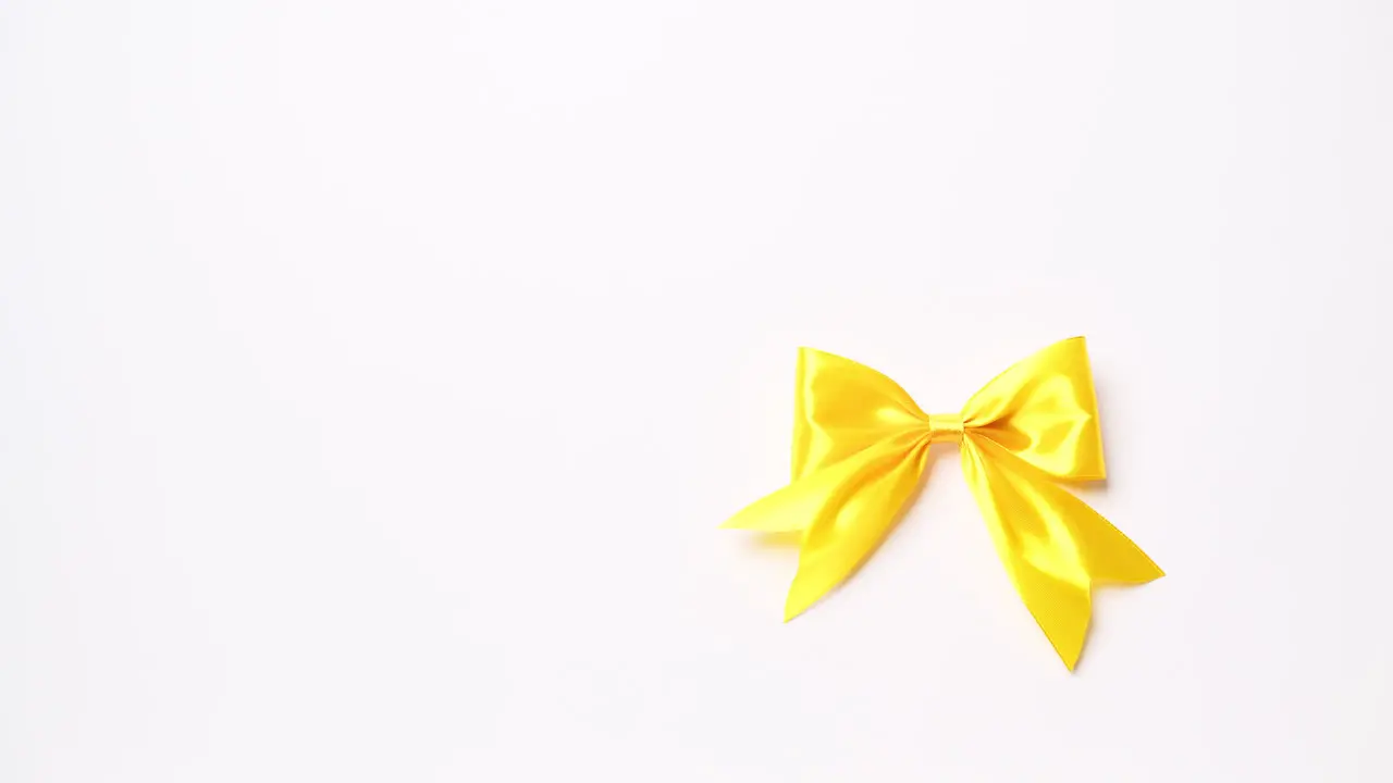 Detail of male hand holding ribbon in yellow color on white background