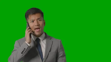 Studio Shot Of Angry Businessman In Suit Talking On Mobile Phone Against Green Screen 1