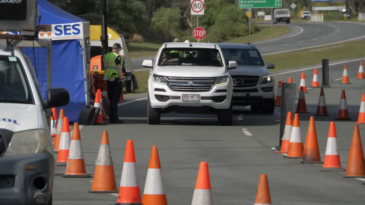 Policeman At Checkpoint Assisting And Talking To A Driver Inside A Car NSW-QLD State Border Coronavirus Pandemic Restrictions In Australia