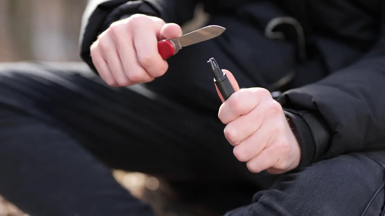 Unrecognizable man sharpening multitool pocketknife on outdoors camping close up