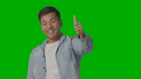 Studio Shot Of Casually Dressed Young Man Giving Thumbs Up Gesture Against Green Screen 1