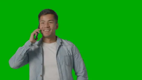 Studio Shot Of Casually Dressed Smiling Young Man Talking On Mobile Phone Against Green Screen 1