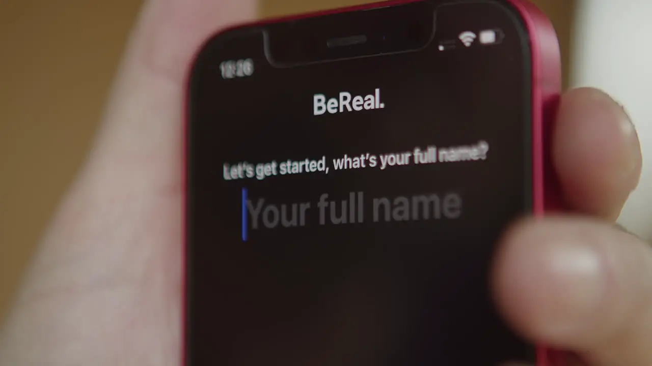 BeReal logo app icon on mobile phone screen finger tapping on display to start application