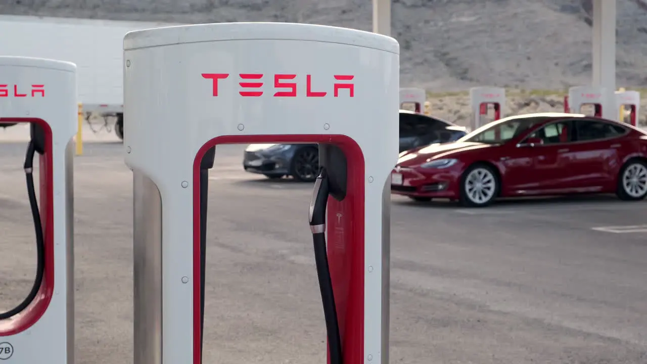 Close Up Of Tesla Supercharger With Tesla's Charging In The Background