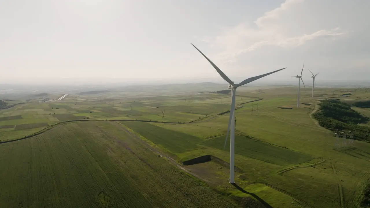 Wind generator turbines slowly rotating above fields of Gori Georgia