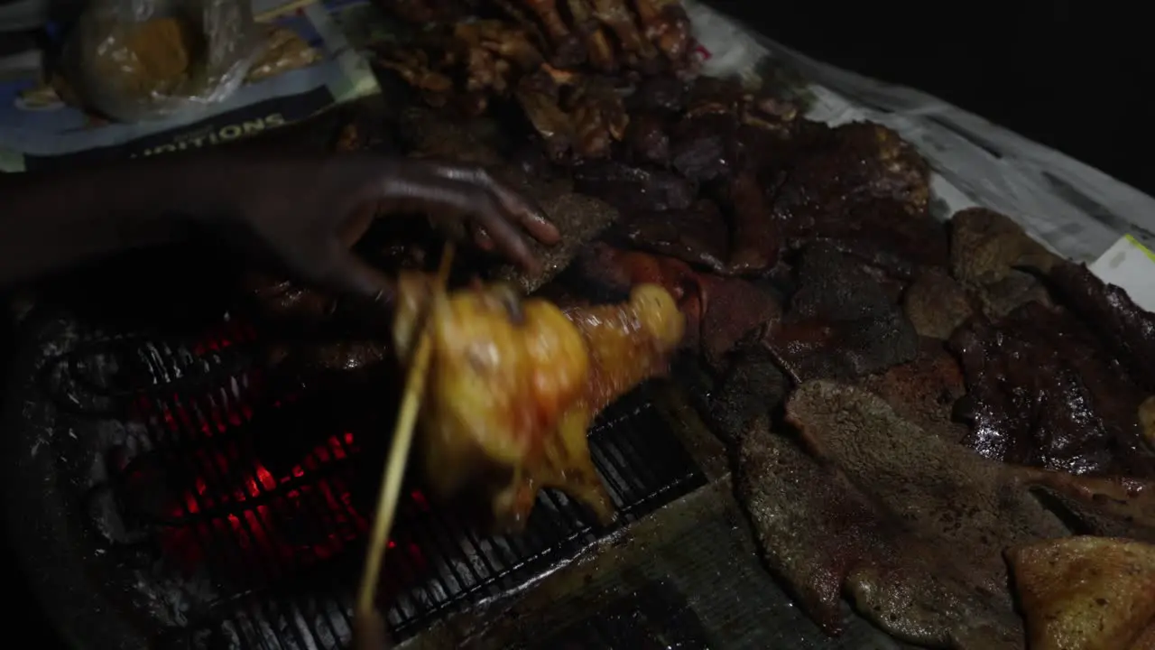 African Street food butcher grills meat on charcoal grill for sale at night